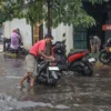 Salah seorang warga sedang mengangkut motornya ditengah banjir di Kota Bandung. (foto/Dam)