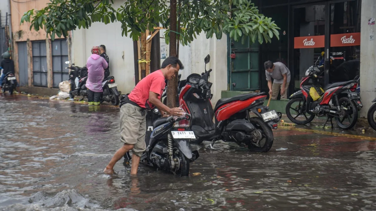 Salah seorang warga sedang mengangkut motornya ditengah banjir di Kota Bandung. (foto/Dam)