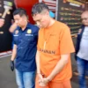 Tertunduk dan diborgol, Dirut BUMD PT PMgS, Deden Robby Firman digelandang polisi usai ditetapkan sebagai tersangka kasus cek kosong senilai Rp659 juta dalam proyek pengadaan ayam beku. Dok Jabar Ekspres/Mong