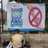 Ilustrasi: Warga berada di depan spanduk sosialisasi SPMB tanpa suap, pungli dan gratifikasi yang terpasang di depan salah satu sekolah dasar di Kota Bandung. Foto: Dimas Rachmatsyah / Jabar Ekspres