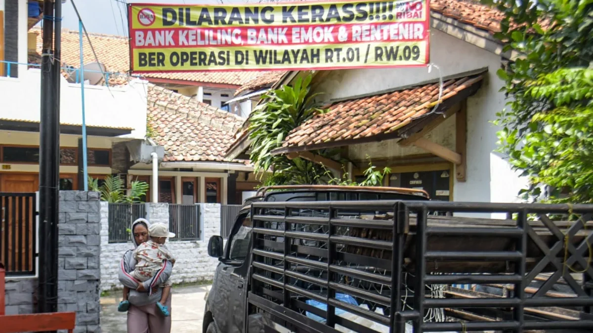 Audiensi dengan Pemkot, Satgas Anti Rentenir Bandung Terima 500 Laporan Warga dalam Setahun Warga berjalan di bawah spanduk peringatan anti rentenir yang terpasang di Kawasan Gunung Batu, Kecamatan Cicendo, Kota Bandung, Rabu (4/6). Foto: Dimas Rachmatsyah / Jabar Ekspres