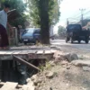 Seorang pria paruh baya sedang berjalan di jembatan kayu untuk menyebrangi saluran air yang sedang dilakukan proyek normalisasi drainase di wilayah Desa Rancaekekwetan, Kecamatan Rancaekek, Kabupaten Bandung. (Yanuar/Jabar Ekspres)