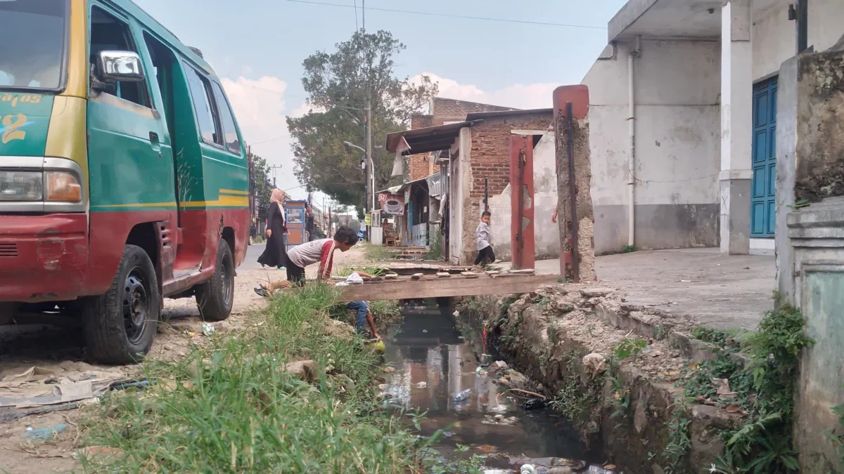 Penampakan jembatan kayu untuk menyebrangi saluran air akibat mangkraknya proyek normalisasi drainase di wilayah Desa Rancaekekwetan, Kecamatan Rancaekek, Kabupaten Bandung. (Yanuar/Jabar Ekspres)
