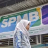 Seorang siswi SMK berjalan di dekat spanduk Sistem Penerimaan Murid Baru (SPMB) di salah satu sekolah di Kota Bandung, Senin (23/6). Foto: Dimas Rachmatsyah / Jabar Ekspres