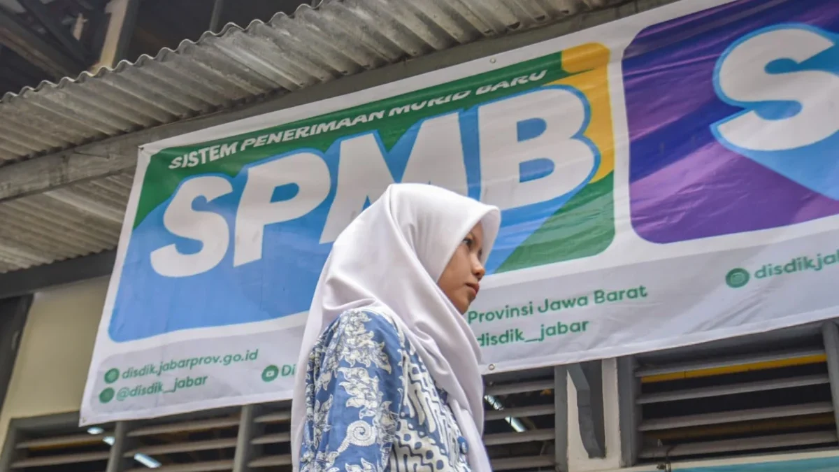 Seorang siswi SMK berjalan di dekat spanduk Sistem Penerimaan Murid Baru (SPMB) di salah satu sekolah di Kota Bandung, Senin (23/6). Foto: Dimas Rachmatsyah / Jabar Ekspres