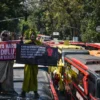 Massa yang tergabung dalam Forum Solidaritas Para Pekerja Pariwisata Jawa Barat (P3JB) membawa spanduk dan men