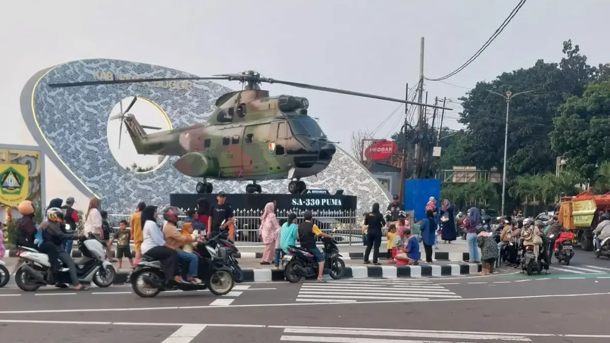 Masyarakat yang memarkirkan kendaraannya di jalan saat sedang berfoto di Tugu Helikopter Simpang Empat Kandang