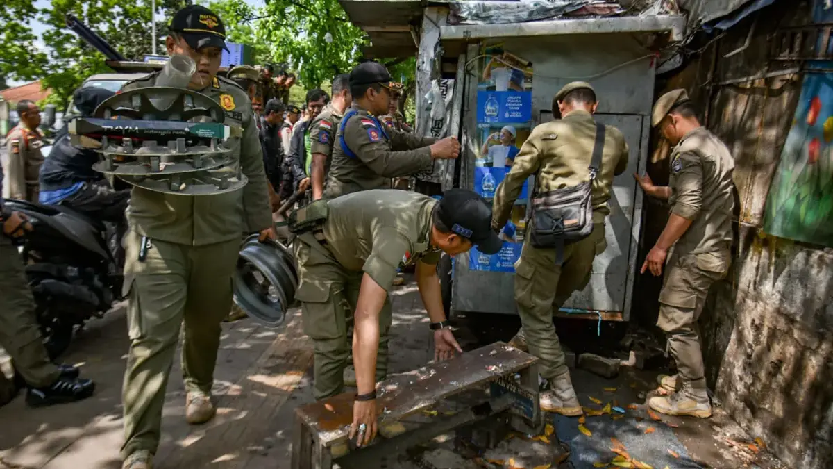 Petugas Satpol PP membawa barang dari salah satu bangunan liar yang dibongkar di Jalan Ibrahim Adjie, Kota Ban