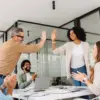 Tim kantor merayakan kesuksesan dengan high-five.