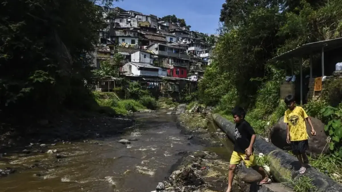 Industri Serap Air Tanah Dinilai Berlebihan, Aktivis Lingkungan: Potensi Konflik Sosial hingga Bencana Ilustrasi: Dua orang anak sedang melintas di atas pipa air di aliran Sungai Cikapundung, Kampung Cibarani, Kot