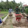 Anggota TNI AD bersama warga setempat bahu membahu memperbaiki jalan rusak yang masuk dalam program TMMD di Ka