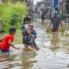Warga membawa tabung gas elpiji melintasi banjir yang menggenangi permukiman di Kampung Bojongasih, Dayeuhkol