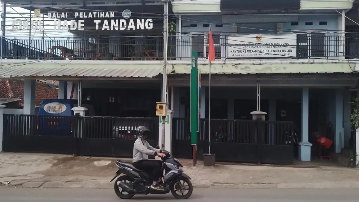 Seorang pria sedang mengendarai sepeda motor melintasi Kantor Desa Cicalengka Kulon, Kecamatan Cicalengka, Kab