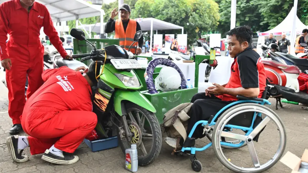 Motor peserta disabilitas sedang ganti oli oleh montir Pertamina Lubricants di acara Pertamina Berbagi bersama
