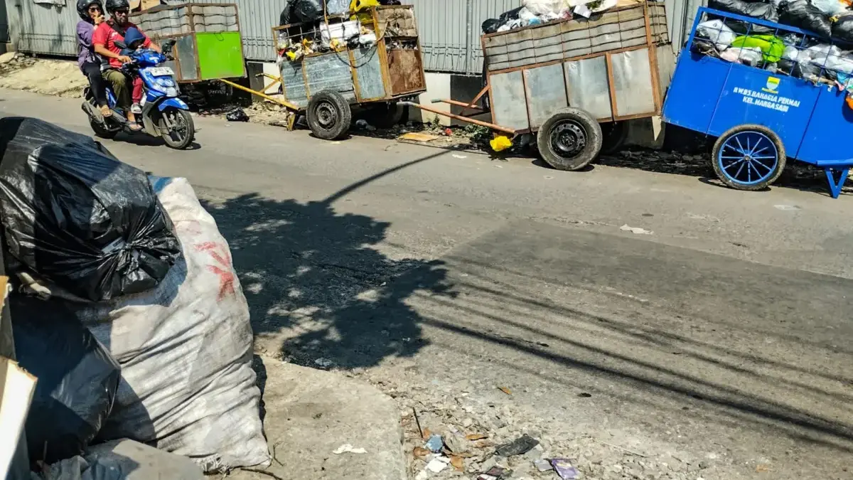 Pengendara melintas disamping gerobak sampah yang berisi penuh sampah di Tempat penampungan sementara (TPS)