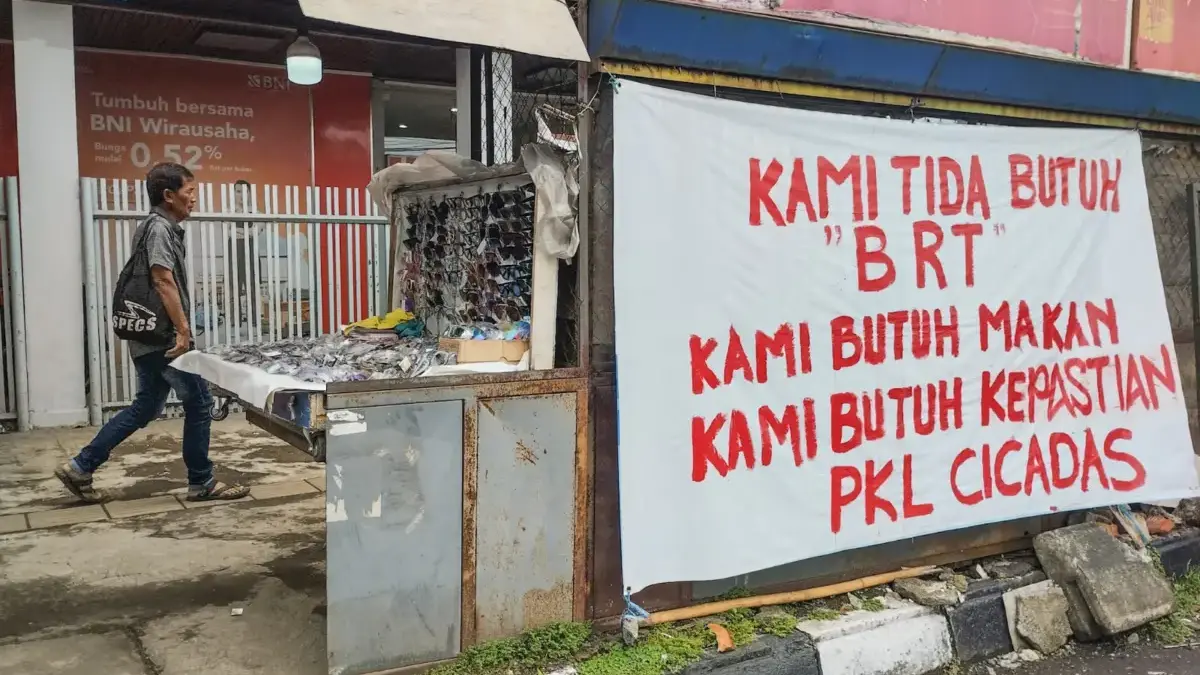 Di Tengah Sepinya Dagangan, PKL Cicadas Dihantui Bayang-bayang Halte BRT Warga berjalan di dekat spanduk keresahan pembangunan jalur Bus Rapid Transit (BRT) yang dipasang