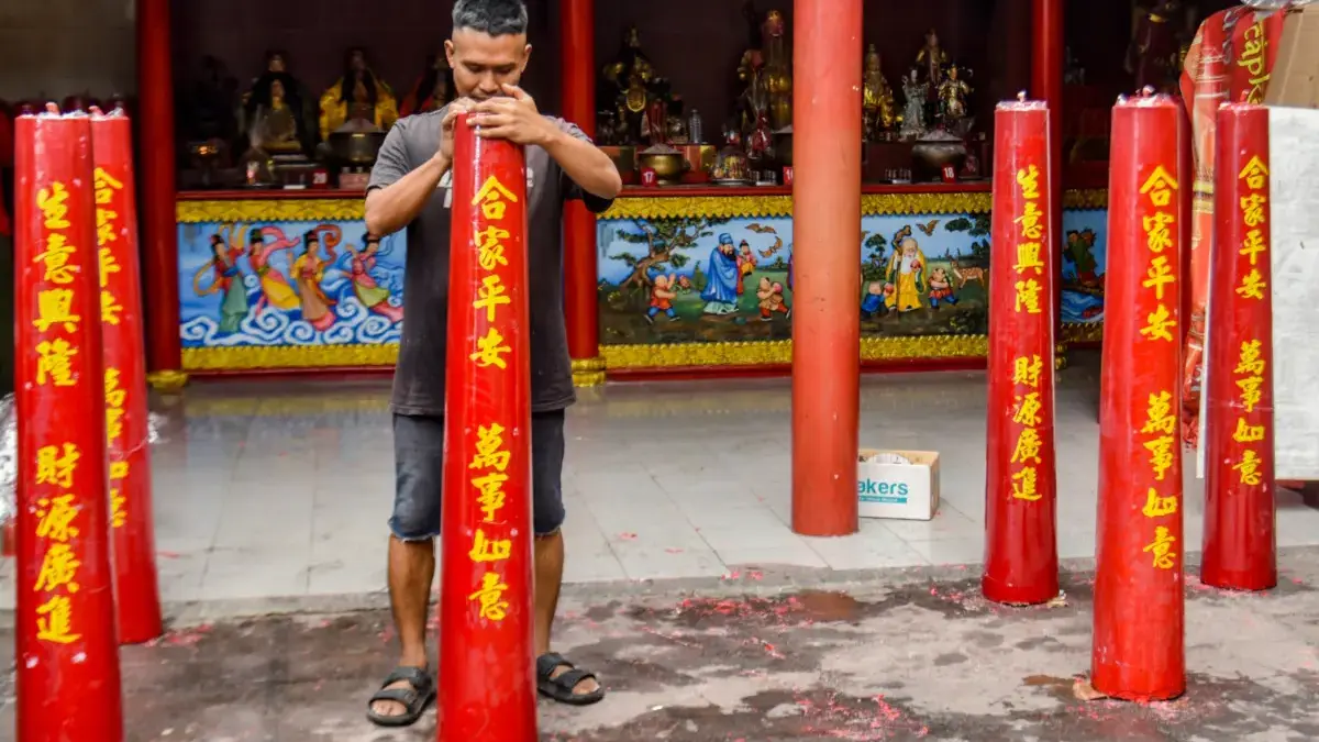 Pekerja menempelkan tulisan di lilin saat produksi di Vihara Dharma Ramsi, Kota Bandung, Kamis (22/1)