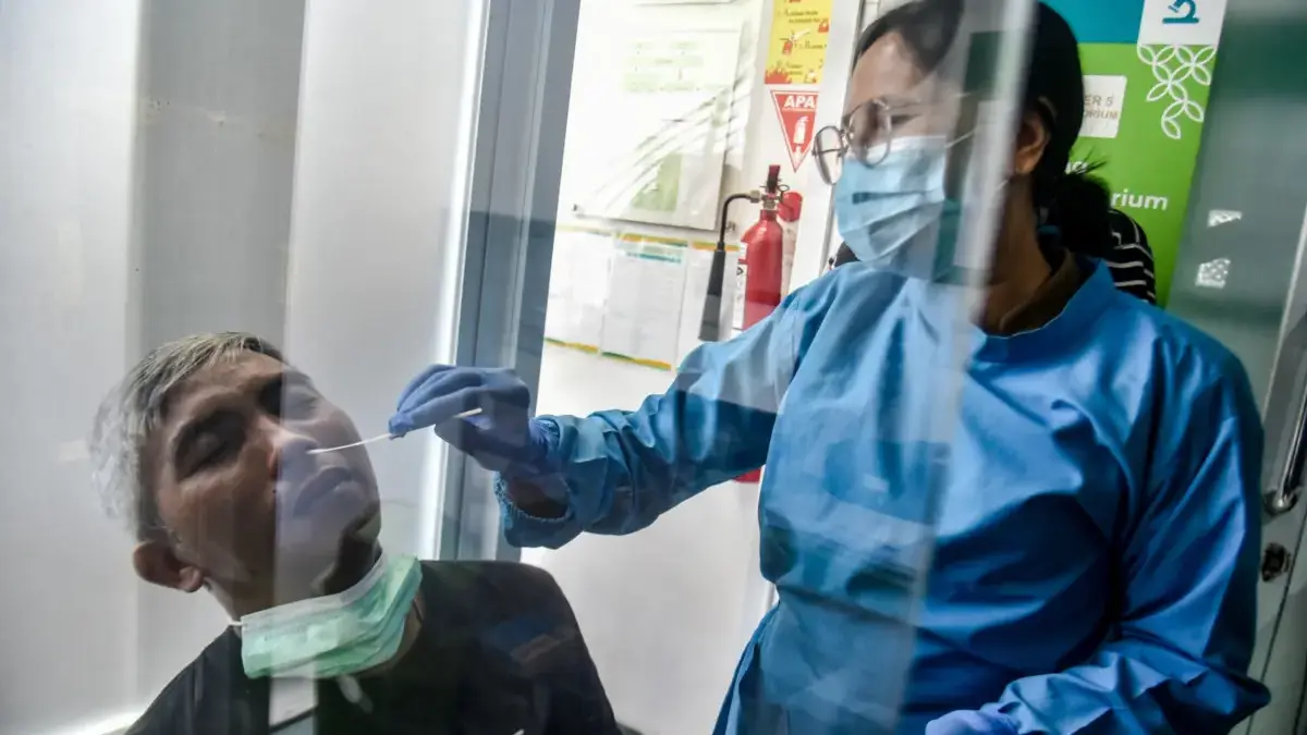 Petugas mengambil sampel dahak seorang pasien saat pemeriksaan deteksi dini superflu di Puskesmas Padasuka, Ko