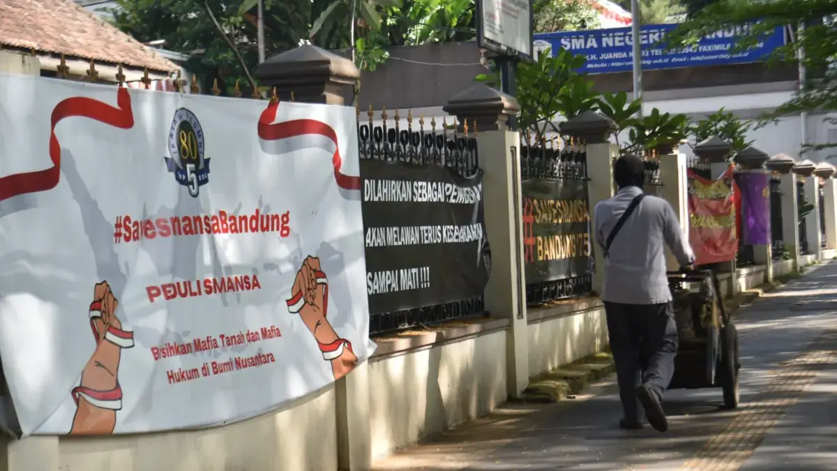 Pedagang berjalan di depan spanduk dukungan di SMAN 1 Kota Bandung, Senin (16/2). Foto: Dimas Rachmatsyah / Ja