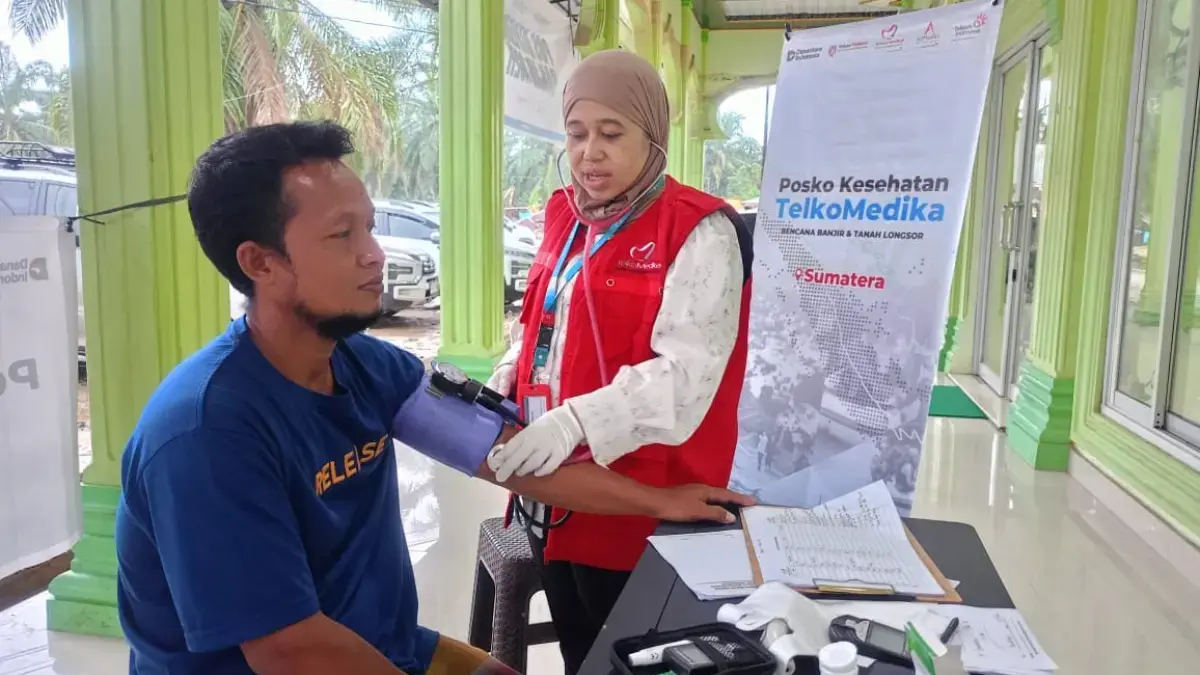 Petugas medis AdMedika dan TelkoMedika melakukan pemeriksaan tekanan darah kepada warga terdampak banjir dan t
