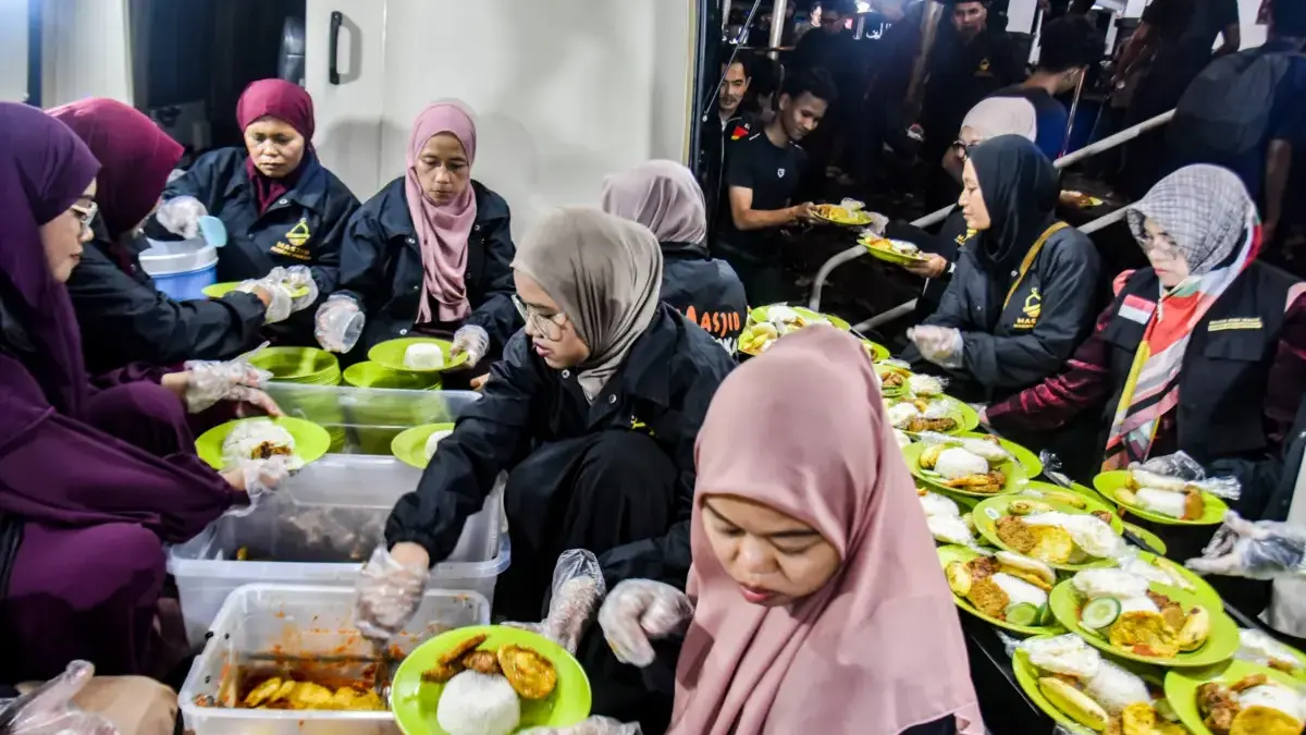 Relawan dari Masjid Makan-Makan membagikan hidangan gratis untuk berbuka puasa kepada jamaah di pelataran Masj