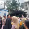 Salah satu warga dengan kupon antrean penukaran uang di layanan penukaran uang dari mobil kas keliling Bank BJ