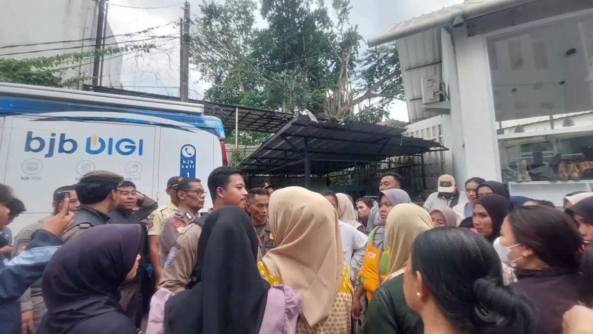 Salah satu warga dengan kupon antrean penukaran uang di layanan penukaran uang dari mobil kas keliling Bank BJ