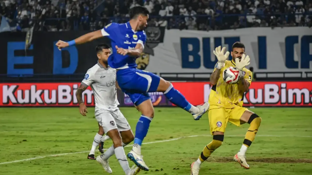 Pemain Persib Bandung Julio Cesar (tengah) menendang bola dan dihalau penjaga gawang Arema FC Lucas Henrique F