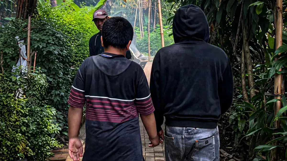 Muhammad Rizki (11) berjalan bergandengan tangan dengan ayahnya, Asep Setiawan, saat pulang ke rumah di Desa G