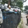 Pelajar berjalan di samping tumpukan sampah yang belum diangkut di TPS Jalan Guntursari Wetan, RW 4