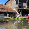 Warga Kampung Bojong Asih, Dayeuhkolot saat melintasi banjir menggunakan perahu. Foto Agni Ilman Darmawan