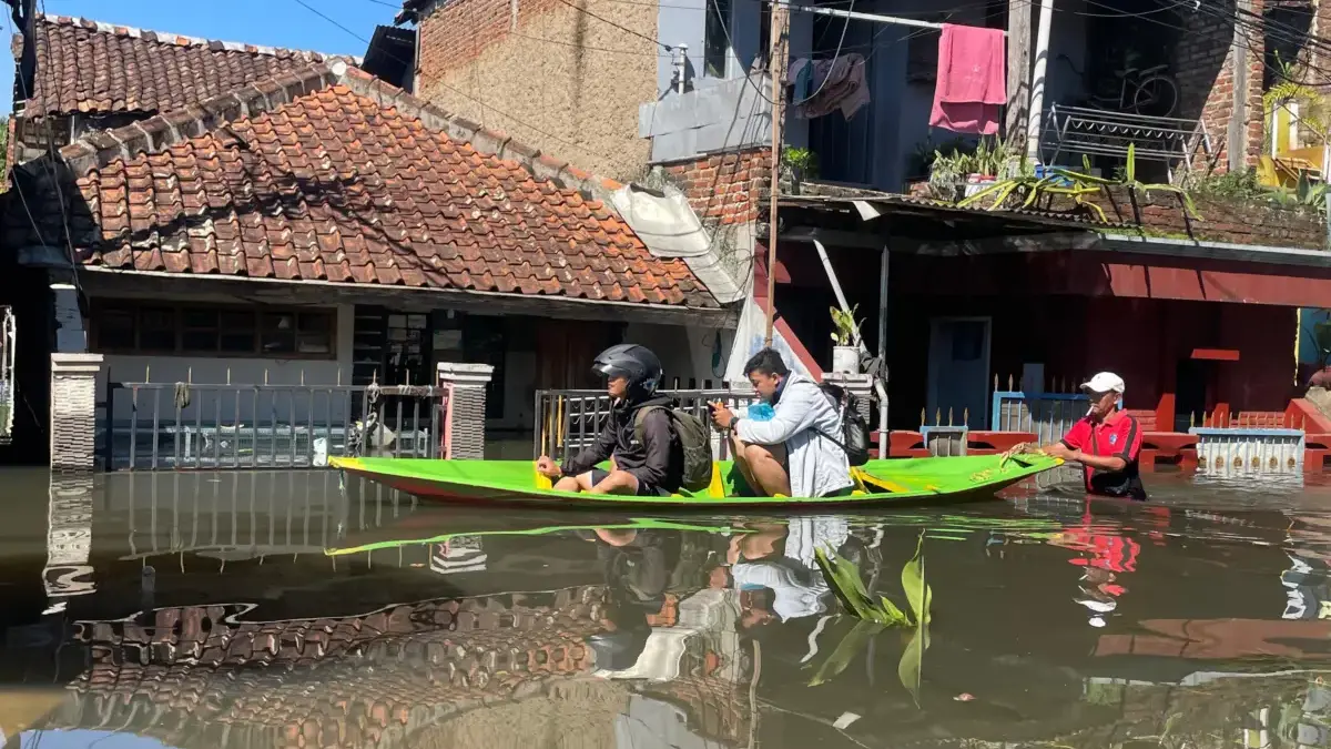 Warga Kampung Bojong Asih, Dayeuhkolot saat melintasi banjir menggunakan perahu. Foto Agni Ilman Darmawan