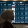 Ilustrasi - Petugas berdiri di dekat layar jadwal penerbangan domestik dan internasional di ruang tunggu Banda