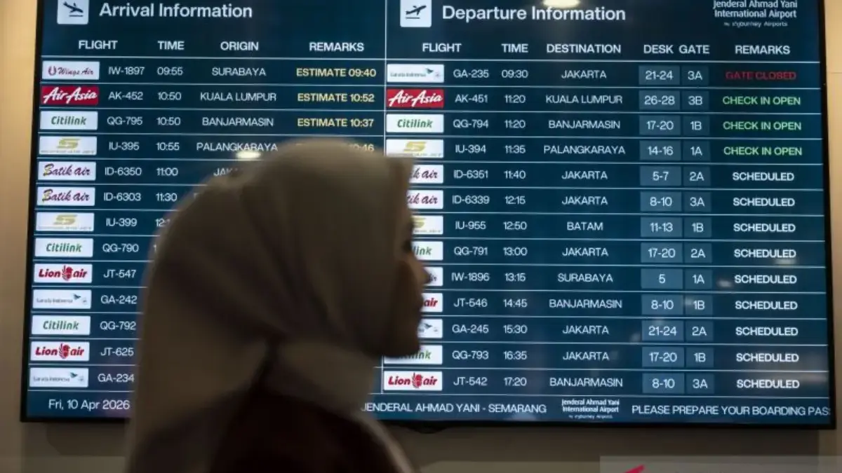 Ilustrasi - Petugas berdiri di dekat layar jadwal penerbangan domestik dan internasional di ruang tunggu Banda