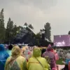 Penonton tetap antusias menikmati festival musik Sunset di Kebun di Kebun Raya Bogor dengan menggunaka jas