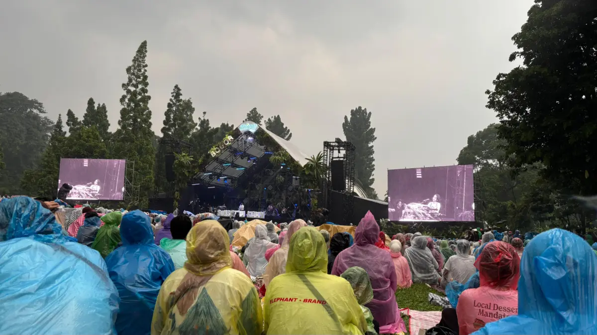 Penonton tetap antusias menikmati festival musik Sunset di Kebun di Kebun Raya Bogor dengan menggunaka jas