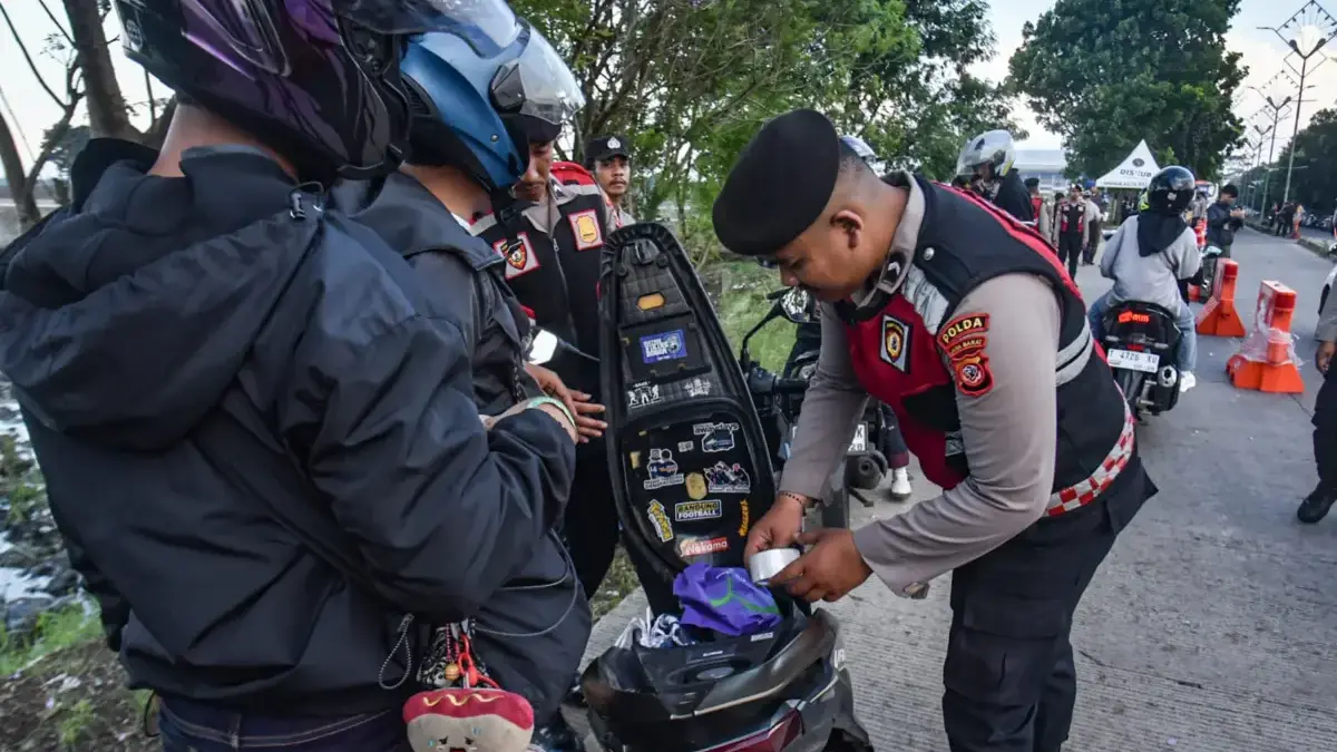Petugas kepolisian saat mengecek barang bawaan suporter sebelum memasuki area stadion GBLA. Foto. Dimas Jabar