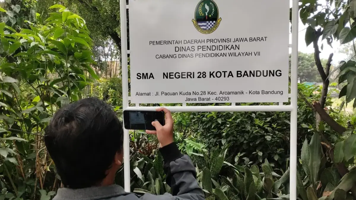 Jurnalis memotret plang penanda SMAN 28 di Jalan Pacuan Kuda, Arcamanik, Kota Bandung, Selasa (9/6/2026)