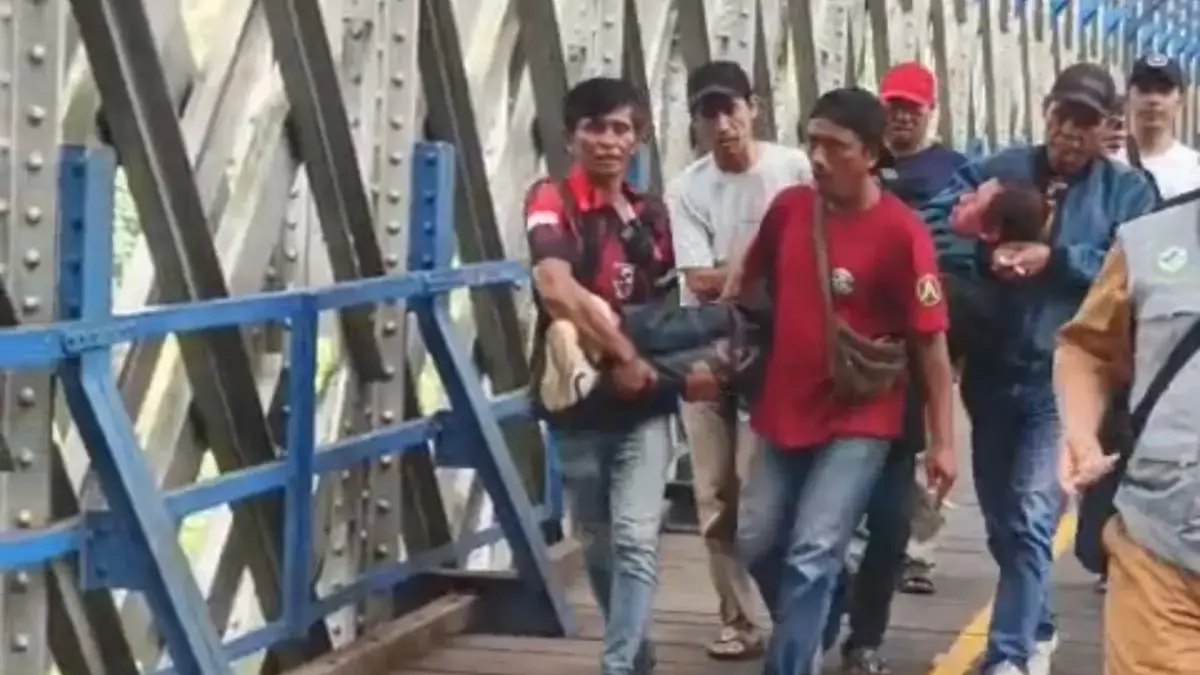 Warga mengevakuasi ODGJ yang nekat berjalan rel kereta api di atas jembatan Cirahong, Senin (16/6/2026).