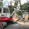 Petugas mengoperasikan alat berat saat penertiban kios bangunan liar di Jalan Singaperbangsa, Kota Bandung