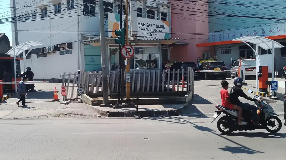 Tampak mesin parkir berwarna oren terpasang di depan gerbang masuk Rumah Sakit Umum Harapan Keluarga yang berl