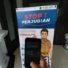Ilustrasi: Seorang warga memotret spanduk stop perjudian di Jawa Barat. Foto: Dimas Rachmatsyah / Jabar Ekspre