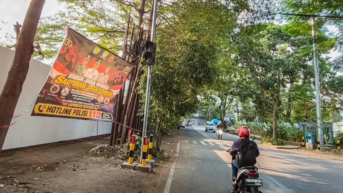 Pengendara sepeda motor melintas di samping spanduk peringatan aksi kriminalitas yang terpasang di Jalan Pasir
