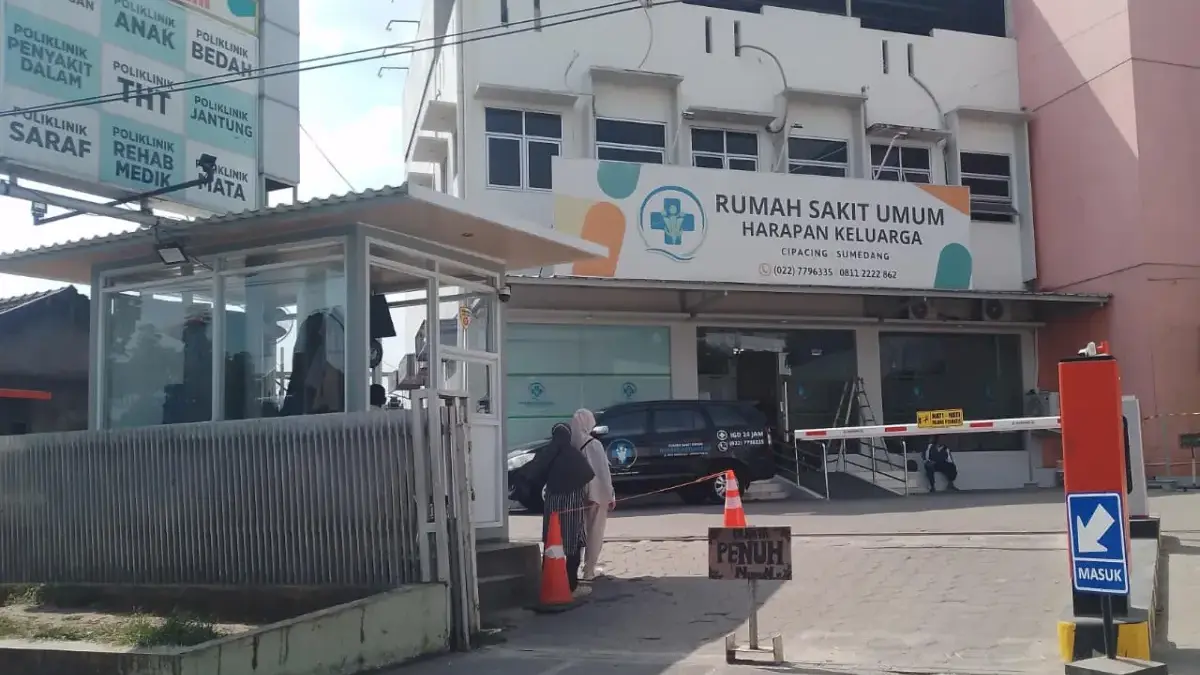 Tampak mesin parkir berwarna oren terpasang di depan gerbang masuk Rumah Sakit Umum Harapan Keluarga yang berl