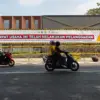 Warga menggunakan sepeda motor melintas di depan garis segel Satpol PP terkait kasus penebangan pohon tanpa iz