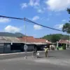 Relawan pengatur lalu lintas kendaraan berdiri di dekat tiang bambu yang digunakan untuk menopang kabel intern