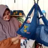 UNIK : Nining Idaningsih saat merangkai dan menunjukkan Tas dari perca denim kreasinya. (Hendrik/JE)