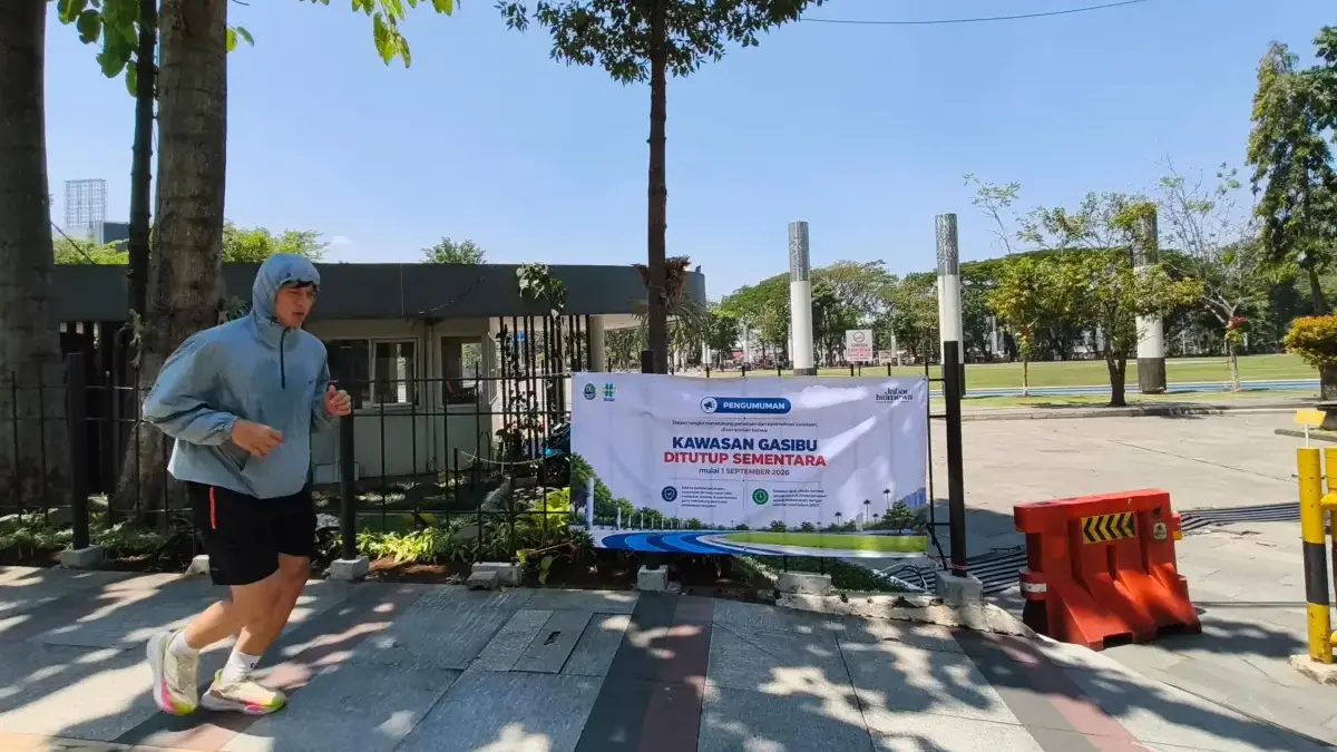 Warga beraktivitas di trotoar di samping spanduk informasi penutupan kawasan Lapangan Gasibu, Kota Bandung, Ra