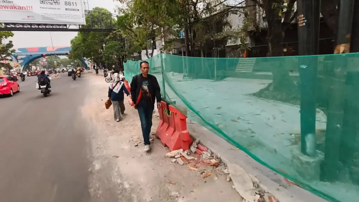 Warga berjalan di samping proyek trotoar di Jalan Ibrahiem Adjie, Kota Bandung, Selasa (1/9/2026). Foto: Dimas