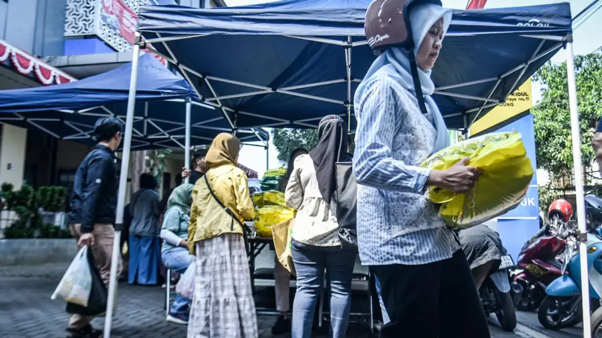 Warga membawa beras SPHP yang telah dibeli saat Gerakan Pangan Murah (GPM) di Kecamatan Cibeunying Kidul, Kota